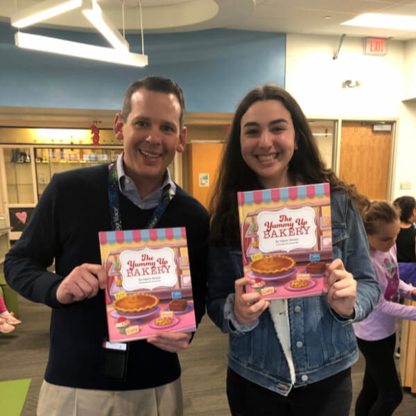 Taylor Hirsch and Teacher posing with Yummy Up Bakery book